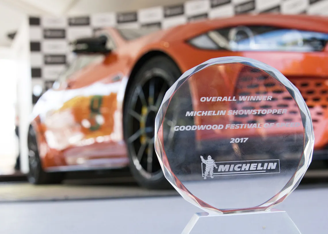 The glass Overall Winner trophy, Michelin Showstopper Goodwood Festival of Speed 2017, in front of an orange supercar.